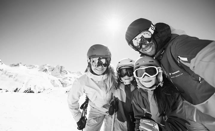 Glad familie på pisten på familieskiferie i Alpe d'Huez med Slopetrotter