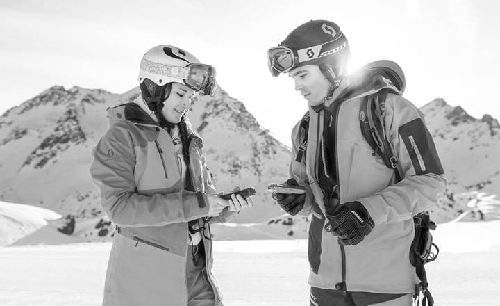 Par tjekker udstyr på sne og bjerge i baggrunden 